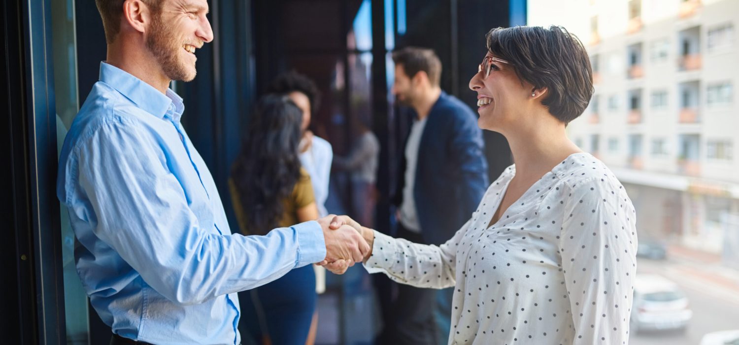 Handshake, meeting and business people on office balcony for welcome, collaboration and partnership. Corporate, professional and man and woman shaking hands for agreement, b2b networking or thank you.
